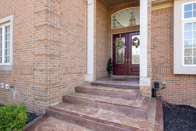 property entrance featuring french doors and brick siding