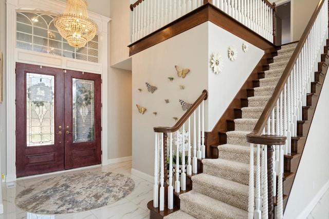 entrance foyer featuring a high ceiling, an inviting chandelier, stairway, marble finish floor, and french doors