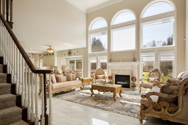 living area featuring crown molding, stairway, a tile fireplace, marble finish floor, and a high ceiling