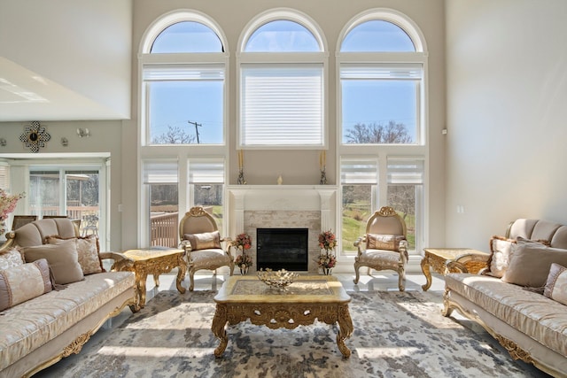living room featuring a towering ceiling, a premium fireplace, and a healthy amount of sunlight