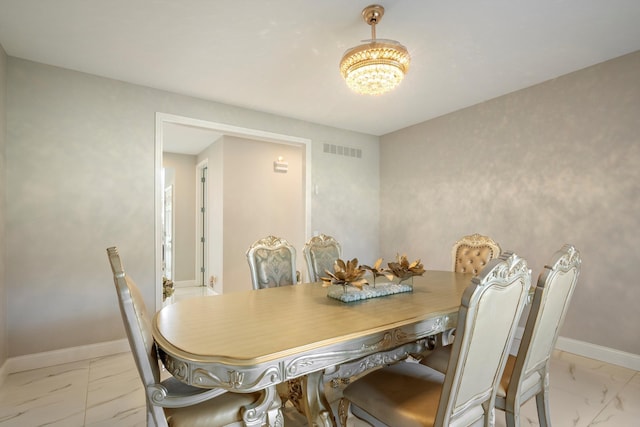 dining room with an inviting chandelier, visible vents, marble finish floor, and baseboards