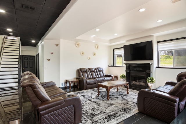 living area featuring visible vents, recessed lighting, stairway, and a glass covered fireplace