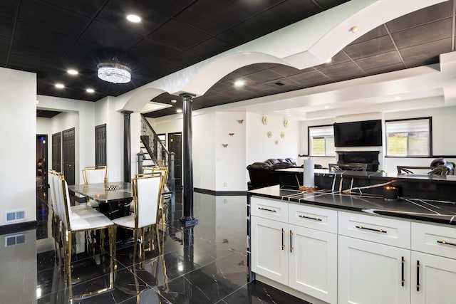 kitchen featuring white cabinetry, visible vents, dark countertops, open floor plan, and ornate columns