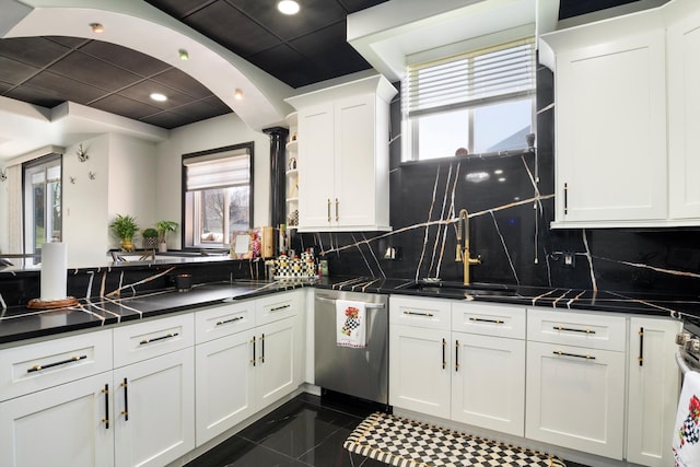 kitchen featuring open shelves, white cabinets, dark countertops, dishwasher, and a sink