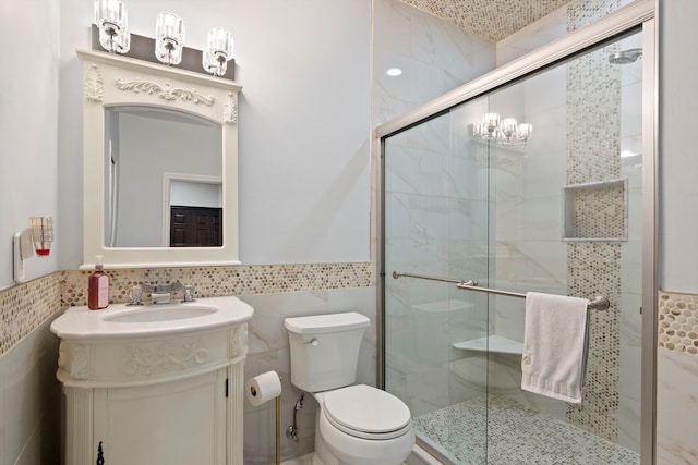 bathroom featuring tile walls, a stall shower, a wainscoted wall, and toilet