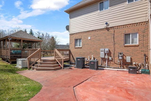 exterior space with a gazebo, central AC unit, a patio area, and brick siding