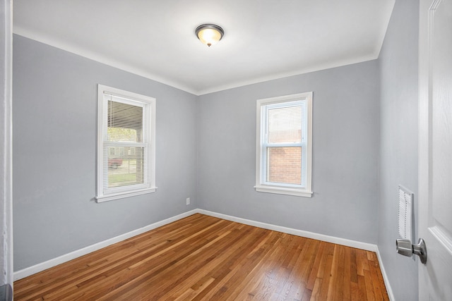 empty room with baseboards, wood-type flooring, and plenty of natural light