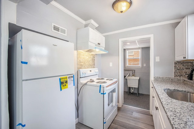 kitchen featuring white cabinets, a sink, visible vents, light wood finished floors, and white appliances