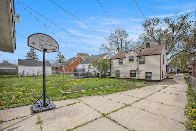 back of property featuring a residential view, a chimney, a shingled roof, fence, and a yard