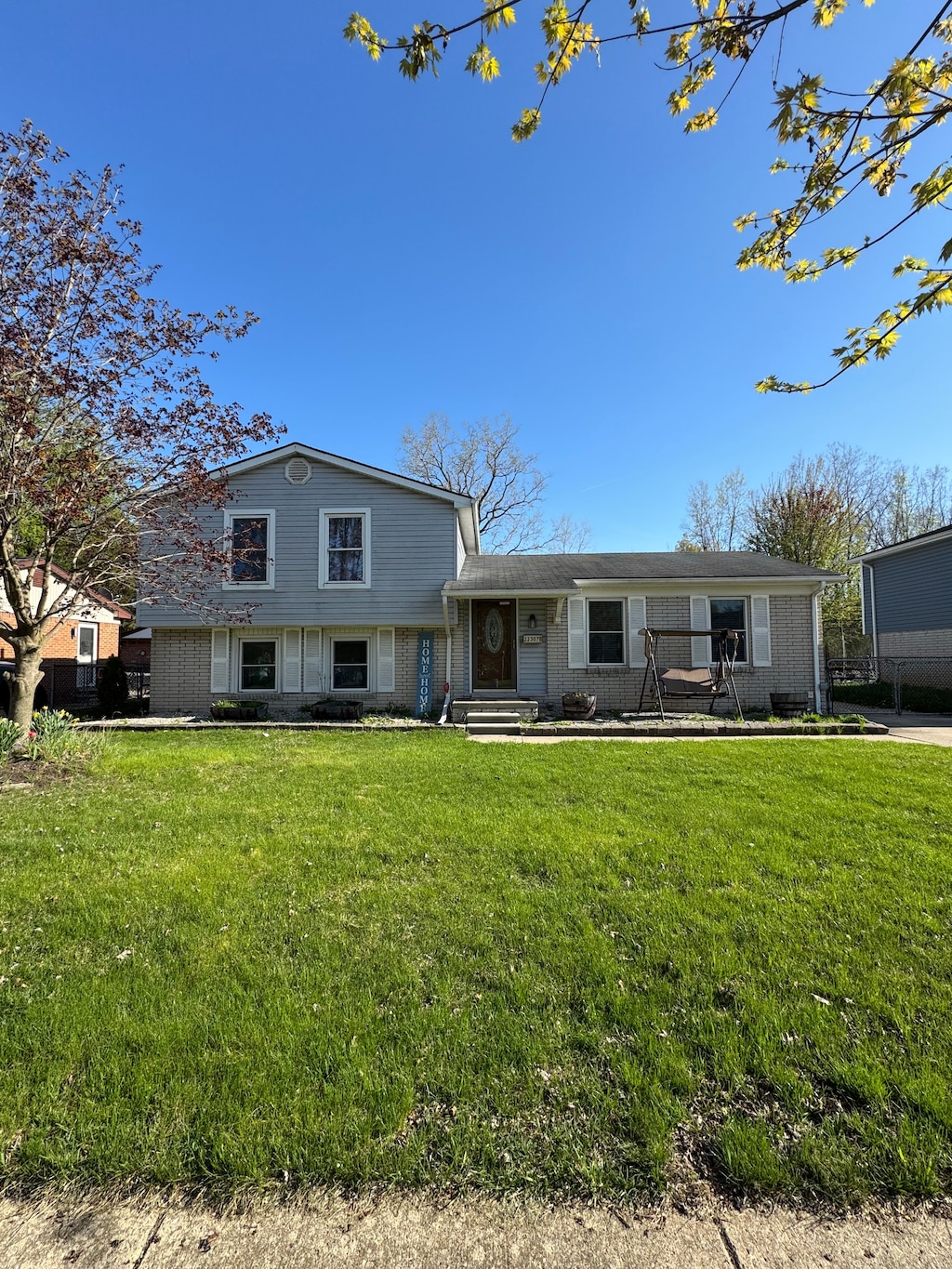 tri-level home with brick siding and a front lawn