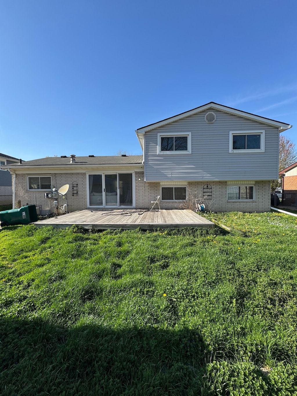 rear view of property with a deck, brick siding, and a yard