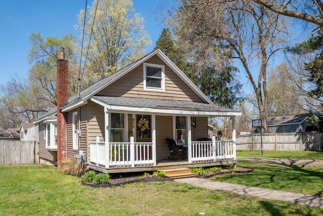 view of front of house with fence, roof with shingles, a chimney, and a front yard