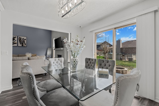 25820 Lord Dr, Chesterfield, MI 48051 - dining space featuring a fireplace, a textured ceiling, wood finished floors, and a notable chandelier