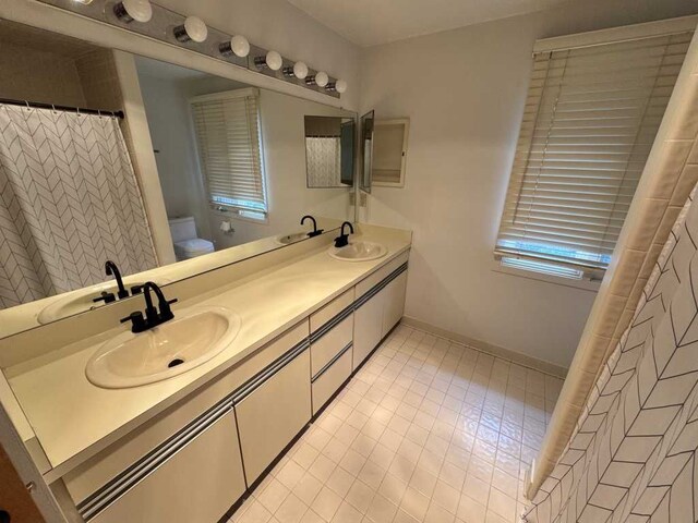 35315 Regency Ln, Farmington Hills, MI 48331 - full bathroom featuring toilet, double vanity, tile patterned floors, baseboards, and a shower with shower curtain