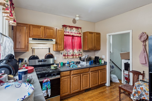2602 Gratiot Ave, Port Huron, MI 48060 - kitchen featuring stainless steel gas range, brown cabinets, a sink, under cabinet range hood, and light wood-style flooring