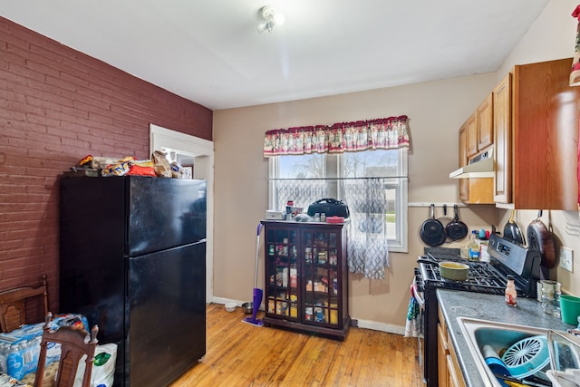 2602 Gratiot Ave, Port Huron, MI 48060 - kitchen featuring brick wall, freestanding refrigerator, light wood finished floors, baseboards, and stainless steel range with gas cooktop