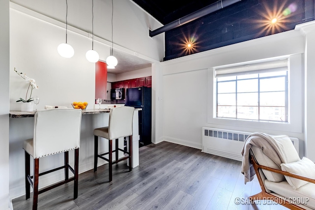 kitchen featuring a kitchen breakfast bar, dark wood-type flooring, black appliances, a towering ceiling, and a peninsula