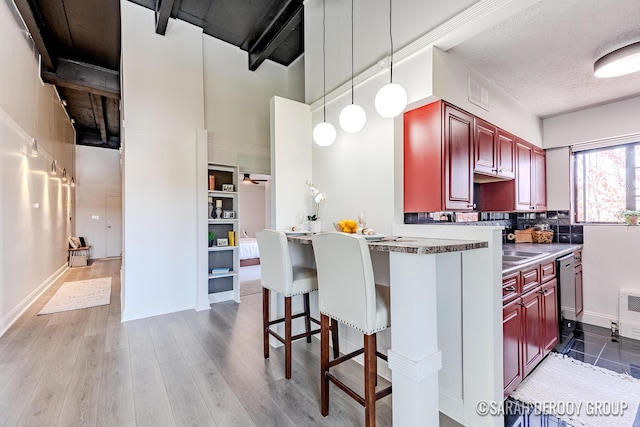 kitchen featuring reddish brown cabinets, wood finished floors, hanging light fixtures, visible vents, and dishwashing machine