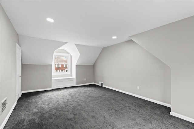 additional living space featuring baseboards, vaulted ceiling, dark carpet, and visible vents
