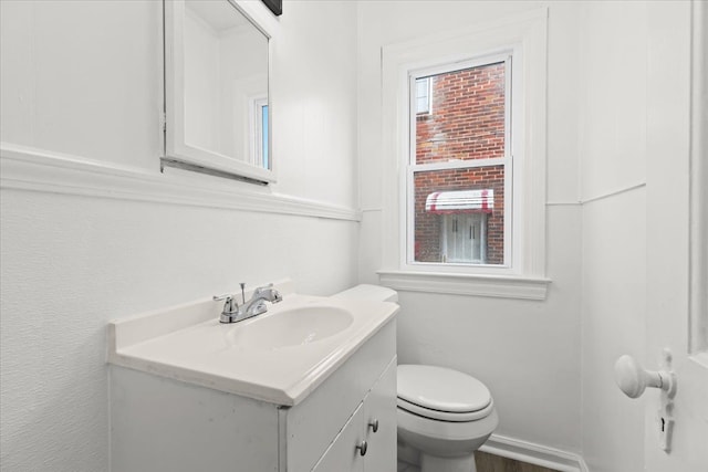 half bath featuring vanity, toilet, and wood finished floors