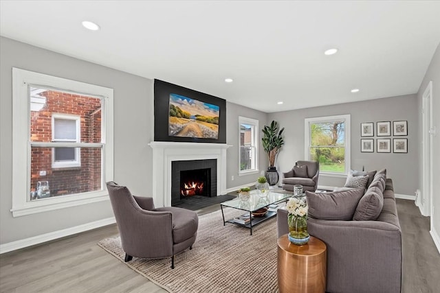 living room with baseboards, recessed lighting, wood finished floors, and a lit fireplace