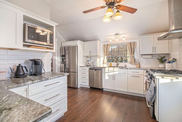 kitchen with a sink, light stone countertops, stainless steel appliances, and wall chimney exhaust hood
