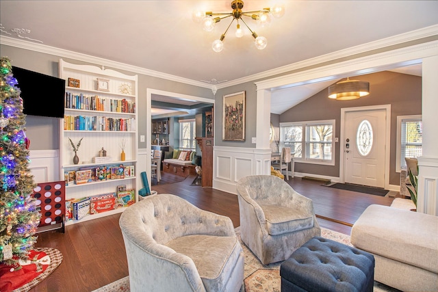 living area featuring crown molding, vaulted ceiling, wood finished floors, an inviting chandelier, and a decorative wall