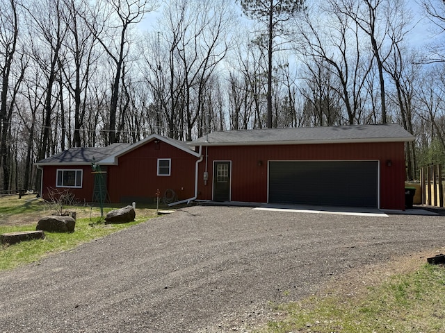ranch-style home featuring driveway, an attached garage, and roof with shingles