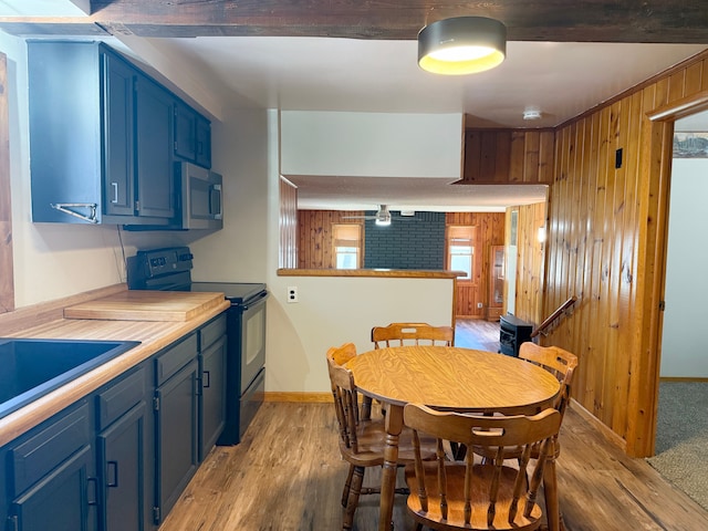 dining space with wooden walls, a healthy amount of sunlight, light wood-style flooring, and baseboards