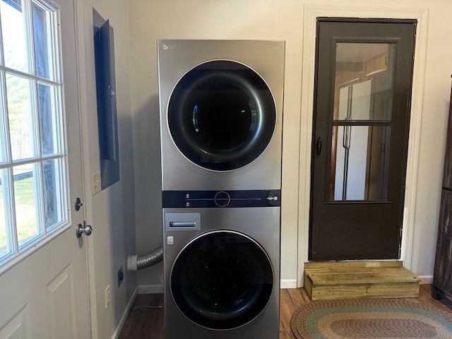washroom with wood finished floors, stacked washer / dryer, laundry area, and baseboards