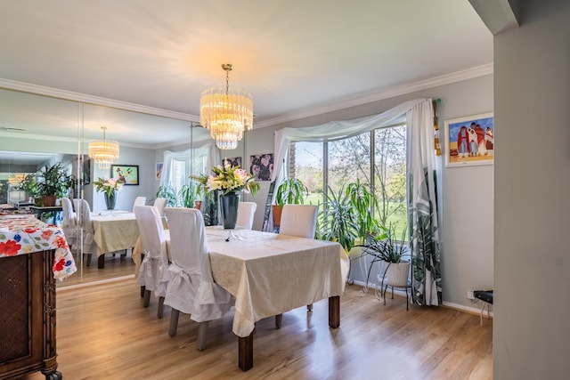 dining area with crown molding, baseboards, light wood-style flooring, and a notable chandelier