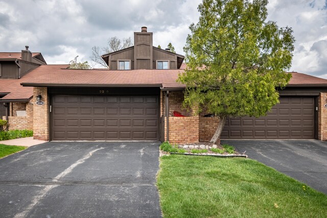 view of front of house with brick siding, driveway, and a chimney