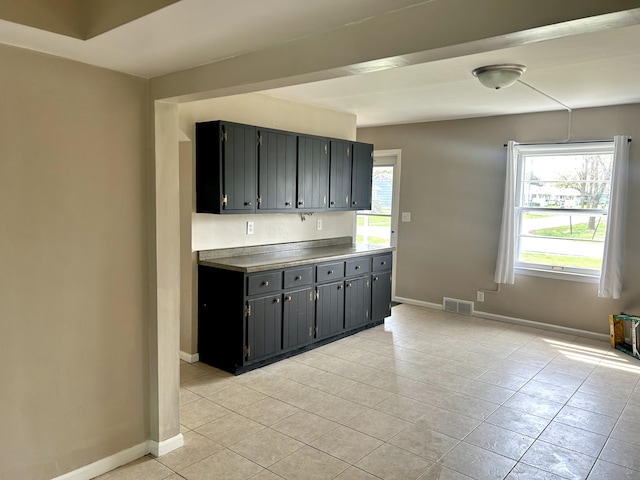 kitchen featuring light tile patterned flooring, visible vents, plenty of natural light, and baseboards