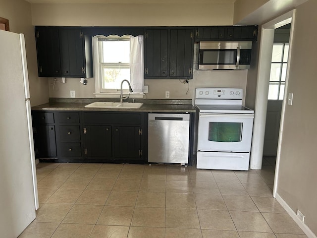 kitchen with stainless steel appliances, dark cabinets, and a sink