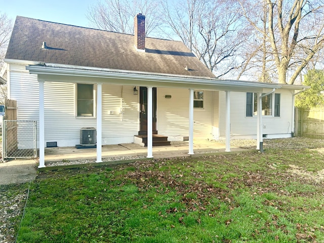rear view of property featuring a chimney, a patio area, a lawn, fence, and central AC unit