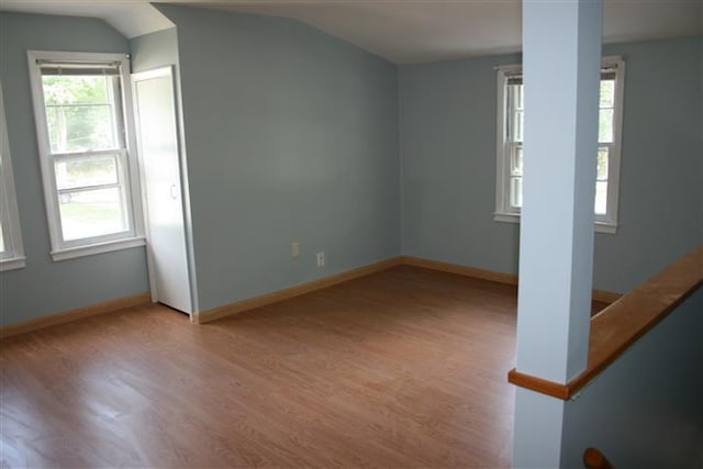 empty room with lofted ceiling, light wood-style floors, and baseboards