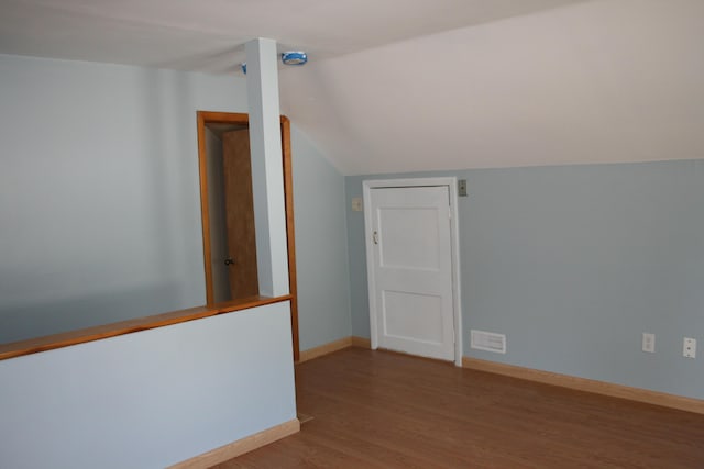 interior space featuring baseboards, visible vents, wood finished floors, and lofted ceiling