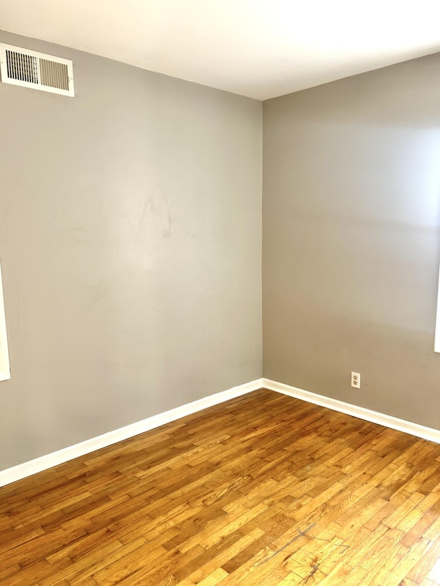 empty room featuring baseboards, visible vents, and light wood finished floors