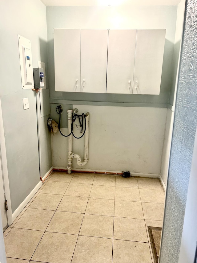 laundry area with washer hookup, light tile patterned floors, electric panel, baseboards, and cabinet space