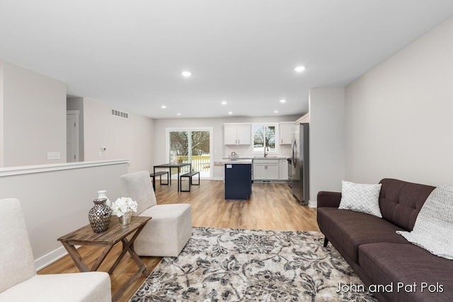 living room featuring baseboards, visible vents, light wood-style floors, and recessed lighting