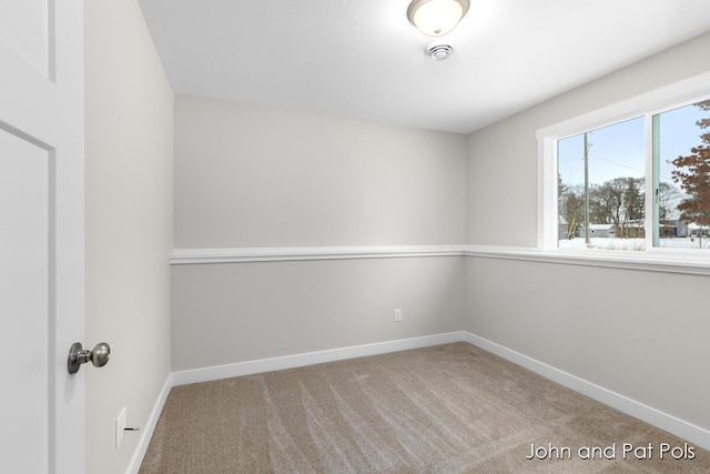 carpeted empty room featuring baseboards
