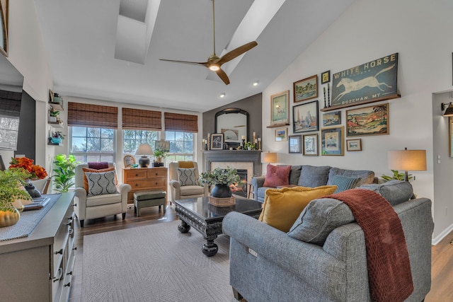 living area featuring a ceiling fan, wood finished floors, lofted ceiling, a glass covered fireplace, and recessed lighting