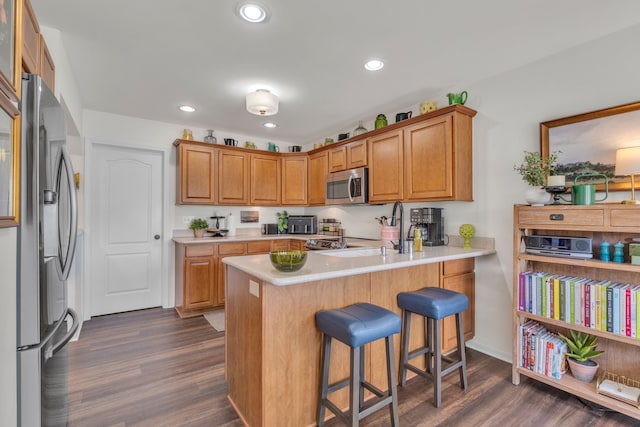 kitchen featuring light countertops, dark wood-style flooring, a peninsula, and stainless steel appliances