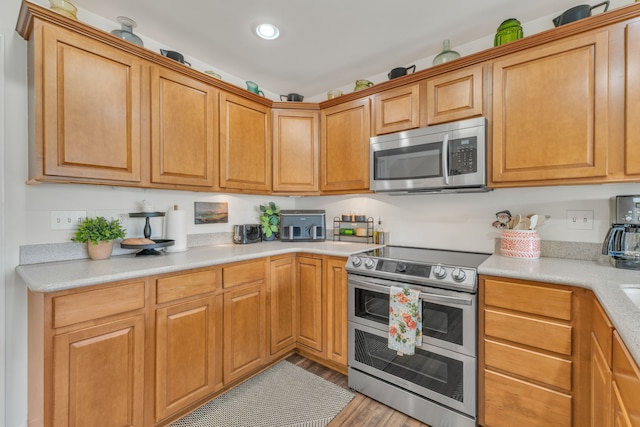 kitchen featuring brown cabinets, light countertops, stainless steel appliances, recessed lighting, and light wood-type flooring