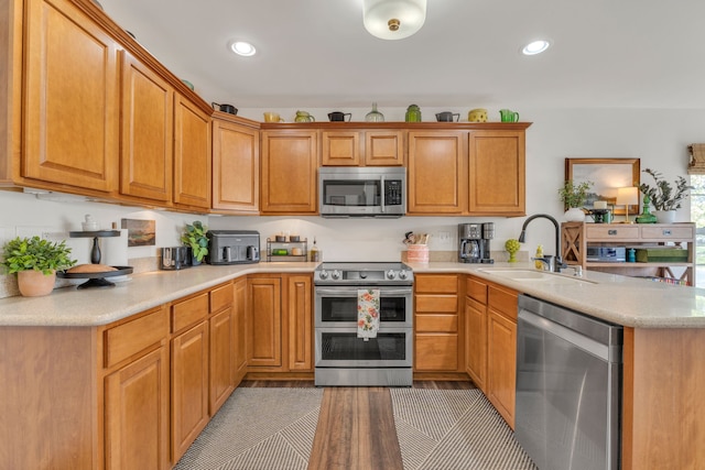 kitchen with a sink, light countertops, stainless steel appliances, recessed lighting, and a peninsula
