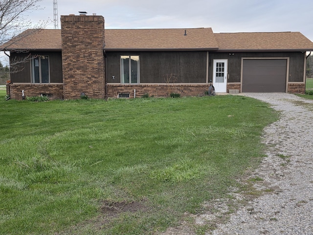ranch-style home featuring a front yard, a chimney, gravel driveway, and a garage