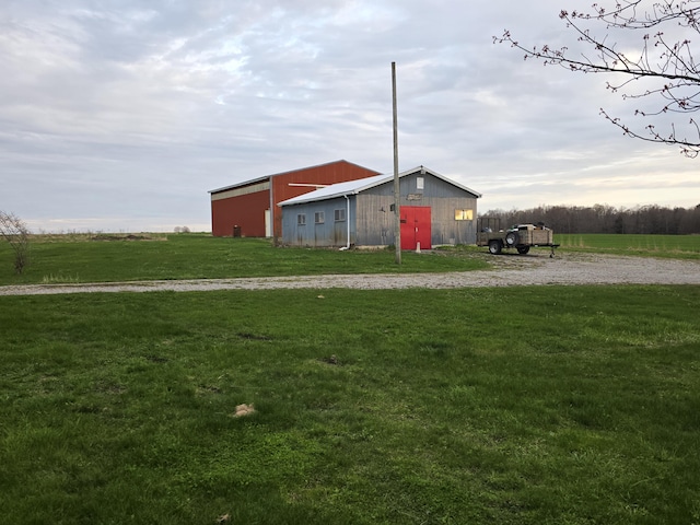 view of pole building featuring a rural view, gravel driveway, and a lawn