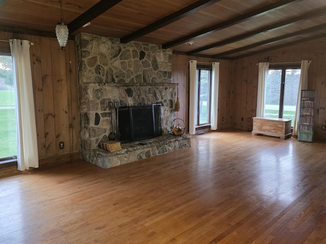 unfurnished living room featuring wooden walls, plenty of natural light, wood finished floors, and a fireplace