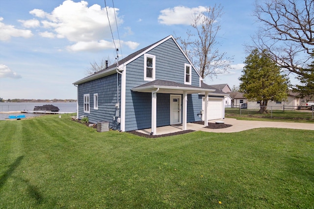 rear view of property featuring fence, concrete driveway, and a yard