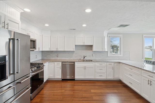kitchen featuring visible vents, ornamental molding, white cabinets, a sink, and stainless steel appliances
